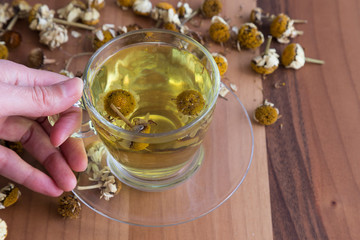 the cup of daisy tea on the wooden background.