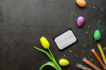 Easter background on black stone. Multicolored eggs and sweets.