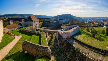 Top view of a part of the old citadel in the city of Besancon. France. The entrance gates, walls, towers and a deep moat are visible. A part of the city is visible in the distance. Scenery. - obrazy, fototapety, plakaty