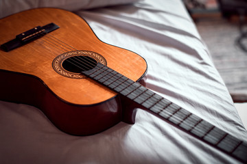 Old wooden acoustic guitar on the bed