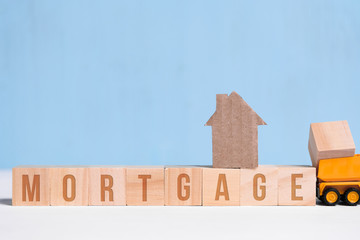 Cardboard cutout house on cubes with inscription mortgage and toy truck.