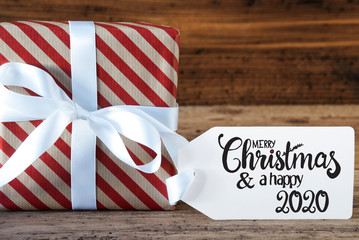 Fototapeta na wymiar One Christmas Gift With Label With English Calligraphy Merry Christmas And A Happy 2020. Wrapping Paper With A Bow