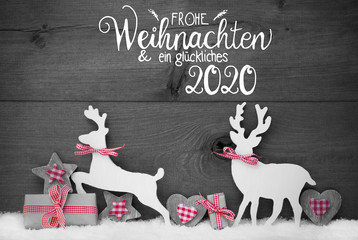 German Calligraphy Frohe Weihnachten Und Ein Glueckliches 2020 Mean Merry Christmas And Happy 2020. Wooden Christmas Ornament Like Present, Heart, And Wooden Deer. Gray Wooden Background With Snow