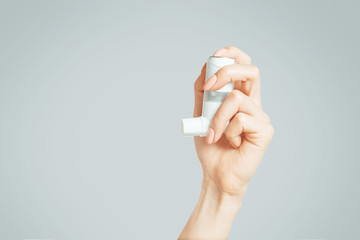 Female hand holding a medical asthma inhaler. - obrazy, fototapety, plakaty