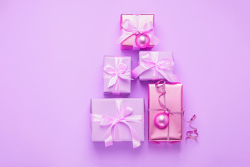 Christmas creative tree gift boxes with shiny balls on a pastel purple pink background. Festive concept of minimalism.