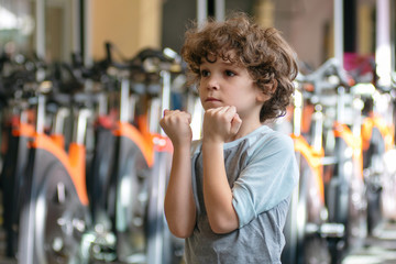 Cute curly 7 year old boy works out at the gym.