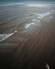 Waves crashing into a sandy beach, dark moody summer photo