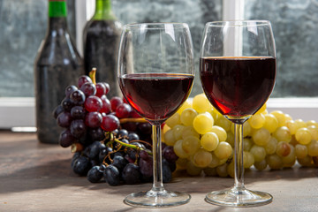 Composition with two wineglasses, grapes and bottles of red wine