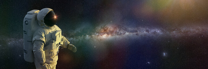 standing astronaut in front of the Milky Way galaxy