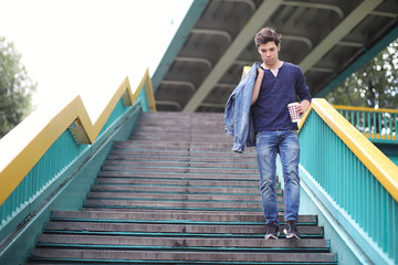 A young man walks in the park at lunch time. A man is on a walk in the city. A student in the park.