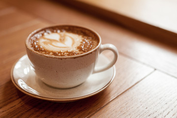 Cup of coffee on wood table, close-up. Cozy pastime in the cafe