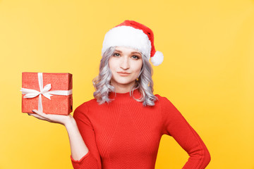 Santa girl holding big golden present and smiling