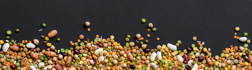 Colorful mixed cereals and legumes on black background. Wide panoramic view.