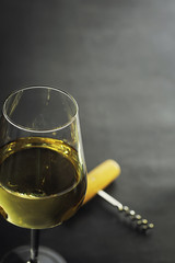 Transparent bottle of white dry wine on the table. White wine glass on a wooden background.