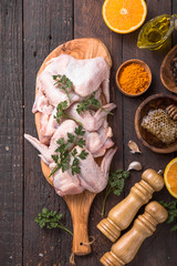 Raw chicken wings with ingredients for cooking: hohey, orange fruit, garlic, olive oil, kari  on a wooden cutting board over wooden background. Top view .