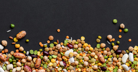 Colorful mixed legumes and cereals on black background.