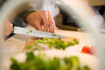 Obraz na płótnie Canvas Close-up of male hands cutting onions with a knife on a kitchen tabkle.
