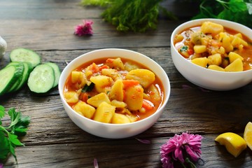 Vegetable stew in a white bowl. Food on a wooden background. Healthy hot meal with potatoes, carrots and parsley.