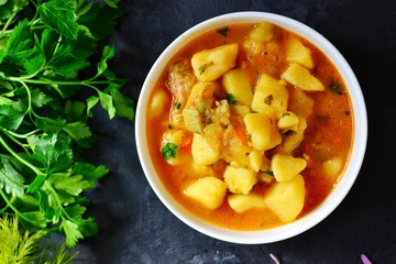 Vegetable stew in a white bowl. Photo food. Stew with potatoes and carrots on a dark concrete background. Healthy vegetarian food.