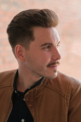 Fototapeta premium portrait of a young guy in a black shirt and brown leather jacket. casual style