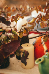 Autumn decor with pumpkin, candles and tableware