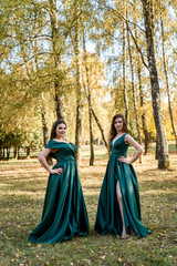 Naklejka premium Ladies in elegant green dresses walking in autumn park. Brunette girl Dreamy young girls laughing on the outdoors