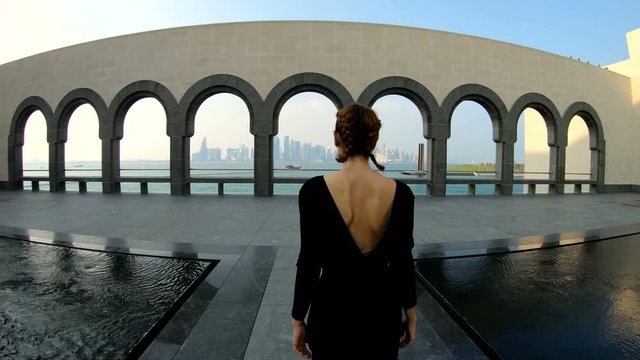 Wide shot of a woman towards a scenic viewing point of the Doha cityscape in Qatar.