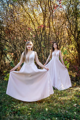 Fototapeta premium Two young princess wearing nice beige dress in autumn park. Fashion photo.
