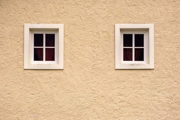 Two windows on a yellow facade  wall of an old fashioned Europe house