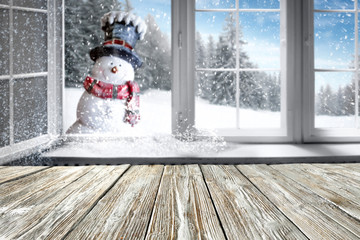 Small smiling snowman in a hat and scarf with white snowy winter background. Space for your...