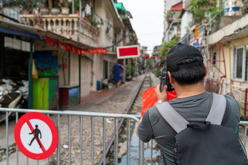 Male tourist taking photo of Hanoi railway next to the "don't walk" sign