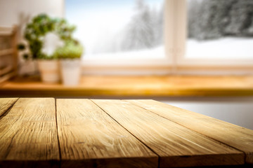 Blurred snowy winter landscape outside the kitchen window with table top for products and decorations.