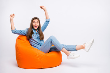 Full length photo of amazed crazy girl sit bag chair watch sport competition victory impressed scream wow omg raise fists wear casual style outfit isolated over white color background - obrazy, fototapety, plakaty