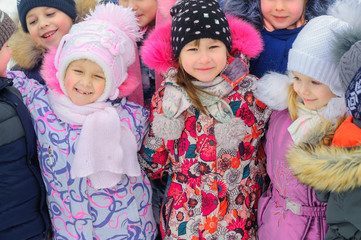 A group of children are playing and having fun on a winter playground. Friends are hugging and smiling. Winter fun. holidays
