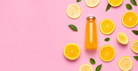 Flat lay composition with glass bottles of juice or fresh, slices of fresh lemon and orange, green...