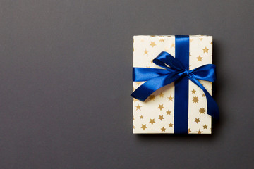 wrapped Christmas or other holiday handmade present in paper with blue ribbon on black background....