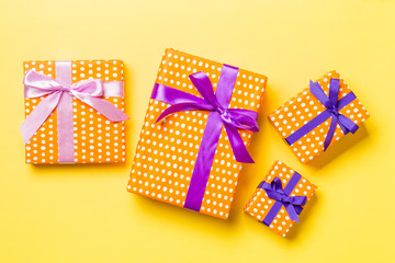 wrapped Christmas or other holiday handmade present in paper with purple and pink ribbon on yellow...