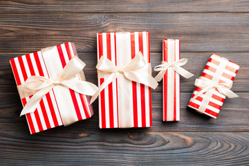 Beautiful gift box with a colored bow on the dark wooden table. Top view banner with copy space for...