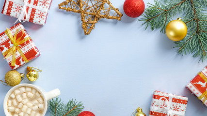 Christmas frame of gift boxes, fir tree branch, festive decorations, balls, coffee cup with marshmallow on pastel blue background. Xmas, winter holiday, New Year concept. Top view, Flat lay.