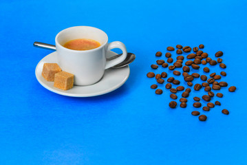 Cup of hot aromatic coffee with sugar cubes on a blue background.