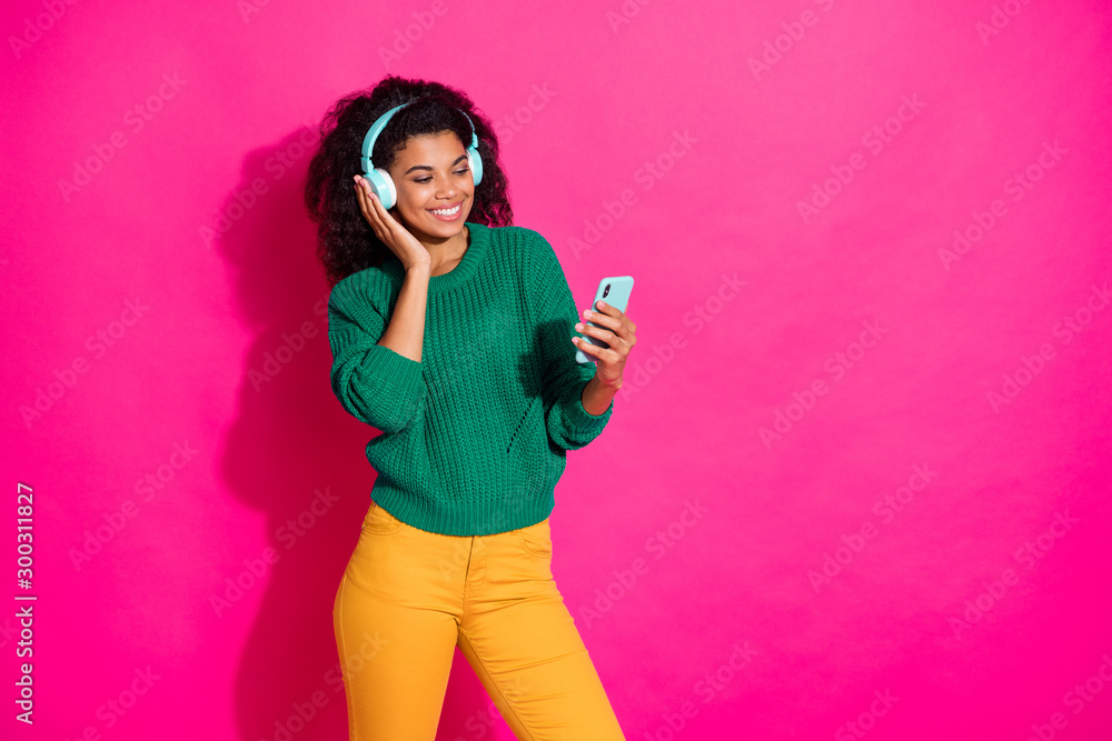 Poster Portrait of positive cheerful girl on autumn fall holiday wear modern headset use smartphone find listen melodies dressed green jumper yellow trendy pants isolated pink color background