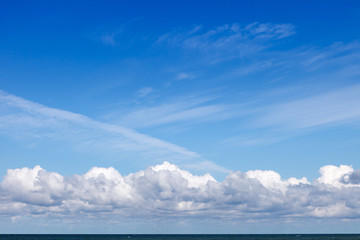 Beautiful blue sky over the sea with translucent, white, Cirrus and Cumulus clouds. Skyline