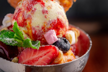 Strawberry ice cream balls with marshmallows, mint, berries and waffles in an iron bowl