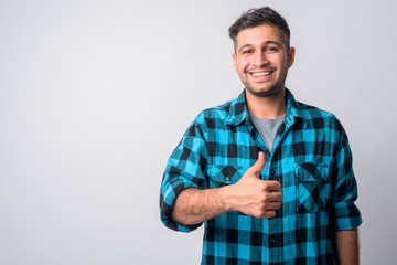 Portrait of happy young Persian hipster man giving thumbs up