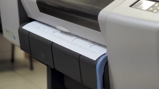 Static shot of Wide format printer, plotter is printing design draft outline sketch drawing in the printing house. Design office supply equipment.