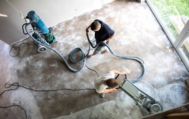 Construction worker in a family home living room that grind the concrete surface before applying...