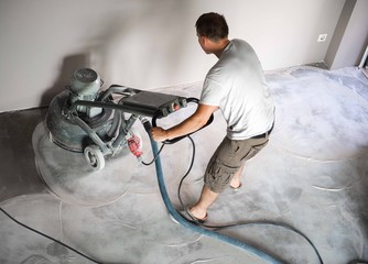 Construction worker in a family home living room that grind the concrete surface before applying...