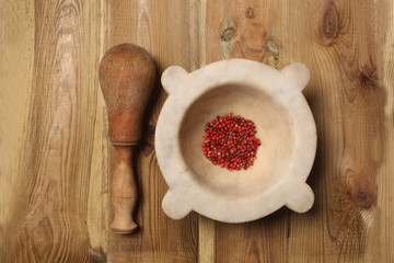 mortar with red pepper grains and pestle on a wooden table view from above with copy space for your text