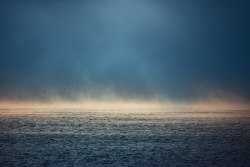 Sea sunrise and foggy morning. Fog above blue ripple water, aerial view