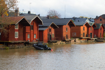 Old red barns on the shore of Porvoonjoki river on a cloudy October day. Porvoo, Finland